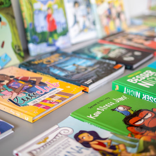 Was braucht ein gutes Kinderbuch? Expert*innen von Save the Children geben persönliche Tipps. © Christoph Schieder / Save the Children Verschiedene Kinderbücher liegen und stehen auf einem Tisch.