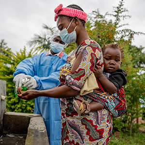 Ebola-Ausbruch: Eine Mutter in der DR Kongo wäscht sich die Hände, um einer Ansteckung vorzubeugen. © Save the Children Eine Mutter mit Baby auf dem Rücken wäscht sich die Hände.